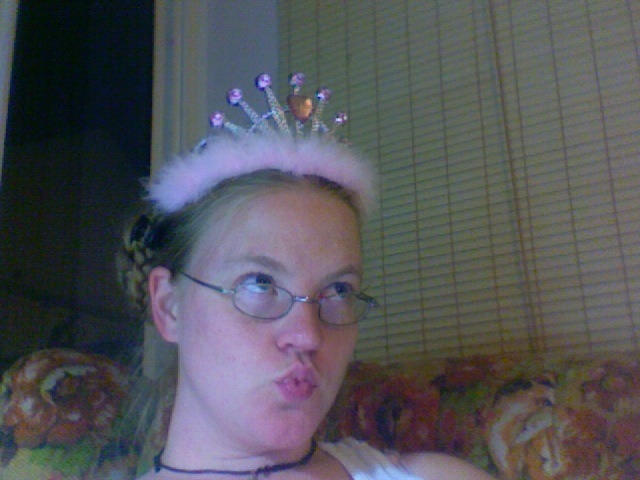 a photograph of the author, a young blonde white woman, duckfacing with a plastic-and-feather tiara on her head
