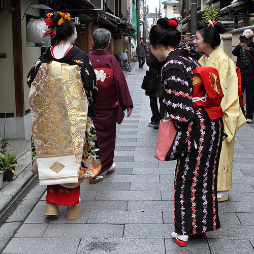 Minarai Toshisumi from Komaya okiya (black kimono) and minarai Koume from Kaden okiya (yellow kimono) greeting maiko Toshimomo (left) for her misedashi.