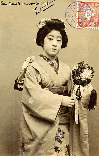 Osaka Geiko z piłką kwiatową (1908) „Ta pocztówka została opublikowana w Sano City w Osace i jest opatrzona stemplem pocztowym Tientsin (Tianjin), Chiny, listopad 1908. Przedstawia Geiko Osaka (Geisha) trzymającego Kusadamę (Kula Kwiatowa ze Wstążkami).  Wygląda jak...