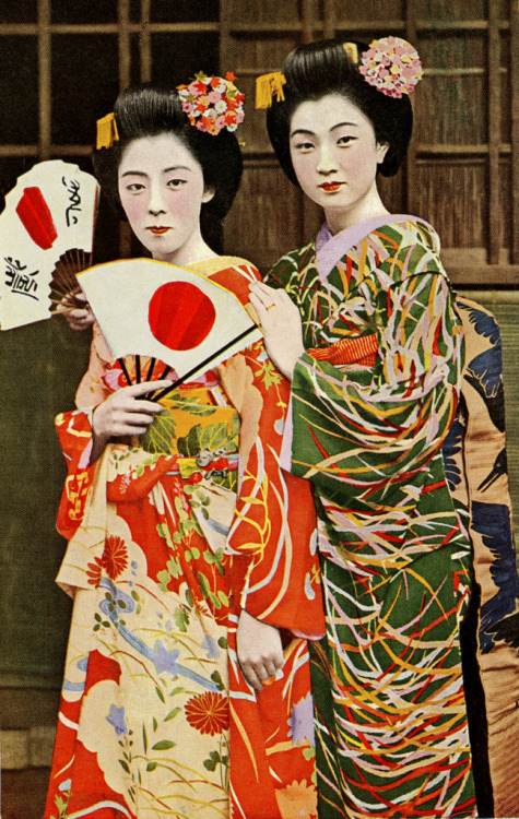 Maiko Fumi and Friend (1940)
“Maiko Fumi on the right-hand side in the green kimono, with another unidentified Maiko (Apprentice Geisha) in orange. A vintage postcard from the late 1930s or early 1940s.” (source)