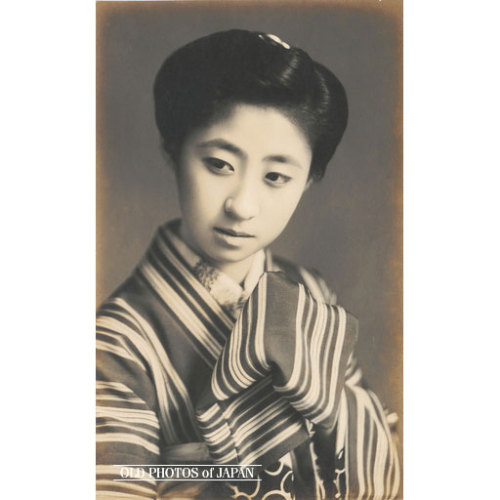 Lata 1910. • Kobieta w kimono w paski „Melancholijny wizerunek młodej Japonki z nieco nowoczesną japońską fryzurą.  Trzyma rękę ukrytą w kawałku materiału blisko brody.  To sprawia, że ​​wygląda bardzo nieśmiało i nieśmiało.  Na początku ...